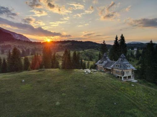 a large house on a hill with the sunset in the background at Nadgora SkyHouse in Žabljak