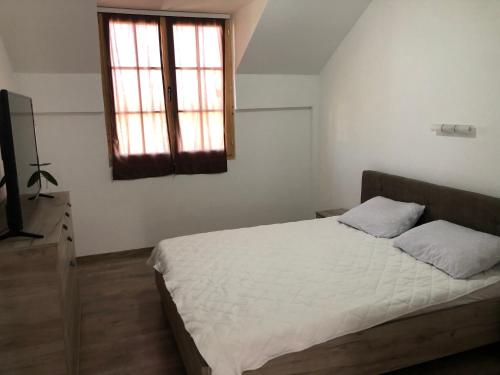 1 dormitorio con cama blanca y ventana en Sunset vila sa bazenom, en Lebane