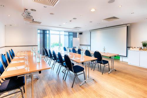 a conference room with tables and chairs and a projection screen at Select Hotel A1 Bremen-Stuhr in Stuhr