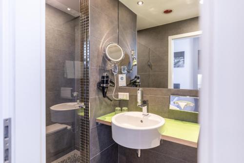 a bathroom with two sinks and a mirror at Select Hotel A1 Bremen-Stuhr in Stuhr