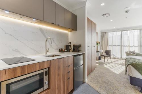 a kitchen with a sink and a bed in a room at Parkside Hotel & Apartments in Auckland