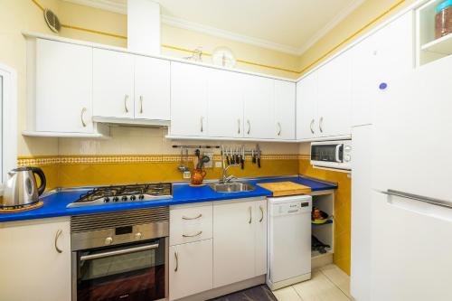 a kitchen with white cabinets and blue counter tops at Es Cantonet in Porto Cristo