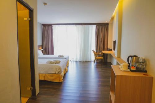 a hotel room with a bed and a large window at Roxy Hotel Serian in Serian