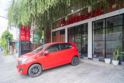 a small red car parked in front of a building at RedDoorz syariah @ Selomangleng Kediri in Kediri