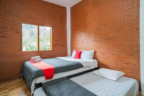 dwa łóżka w pokoju z ceglaną ścianą w obiekcie RedDoorz syariah @ Selomangleng Kediri w mieście Kediri