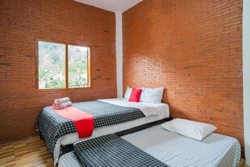 two beds in a room with a brick wall at RedDoorz syariah @ Selomangleng Kediri in Kediri