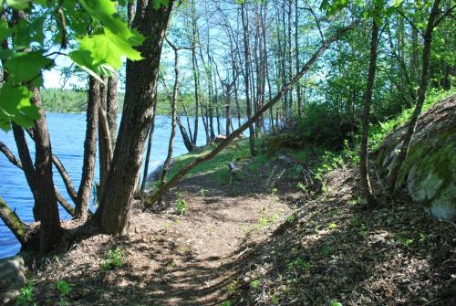 a trail next to a body of water with trees at Kirjakkalan Ruukkikylä in Teijo