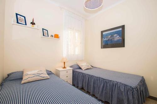 two twin beds in a room with two beds sidx sidx sidx at Maresme Beach Apartment in Canet de Mar