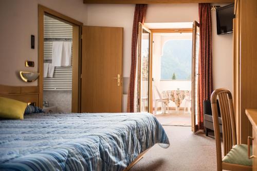 a hotel room with a bed and a balcony at Hotel Sonne Sole in Vigo di Fassa
