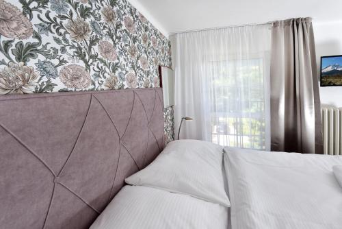 a bedroom with a bed and a floral wall at APLEND Hotel Lujza Major in Tatranská Lomnica