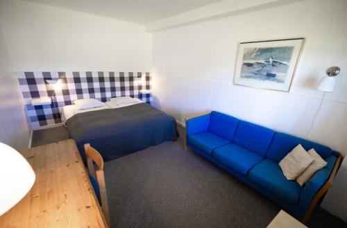 a small room with a blue couch and a bed at Tylstrup Kro og Motel in Tylstrup