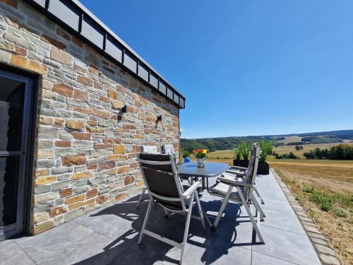 a patio with a table and chairs on a stone wall at Ferienwohnung Kessler's Eifeldomizil in Auw
