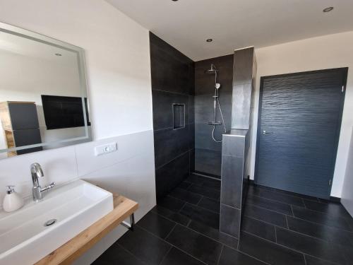 a bathroom with a shower and a sink and a mirror at Ferienwohnung Kessler's Eifeldomizil in Auw