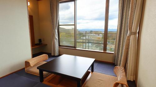 a room with a table and chairs and a large window at Arima Onsen Taketoritei Maruyama in Kobe
