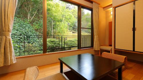 a living room with a table and a large window at Arima Onsen Taketoritei Maruyama in Kobe