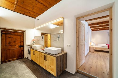 a bathroom with two sinks and a door to a bedroom at Unterlanpacher Historic Refugium in Laces