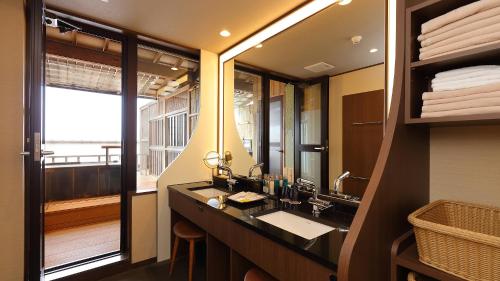 a bathroom with a sink and a mirror at Arima Onsen Taketoritei Maruyama in Kobe
