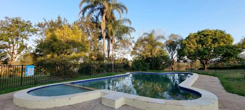 einen Pool in einem Garten mit einem Zaun und Bäumen in der Unterkunft Y Motels Gympie in Gympie