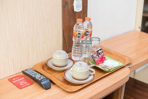 a table with a tray with drinks and a remote control at RedDoorz Plus Syariah @ Jalan Dokter Wahidin Bojonegoro in Bojonegoro