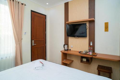 a hotel room with a bed and a television at RedDoorz Plus Syariah @ Jalan Dokter Wahidin Bojonegoro in Bojonegoro
