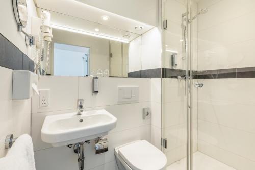 een badkamer met een wastafel, een toilet en een douche bij Select Hotel Osnabrück in Osnabrück