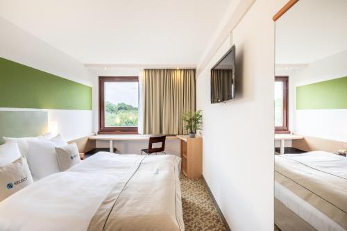 オスナブリュックにあるSelect Hotel Osnabrückのベッド2台とデスクが備わるホテルルームです。