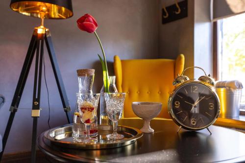 una mesa con gafas y un reloj y una rosa en Priedes māja en Ainaži