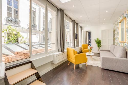 - un salon avec des fenêtres et une chaise jaune dans l'établissement Cosy 5 bedrooms with patio - Louvre Museum, à Paris