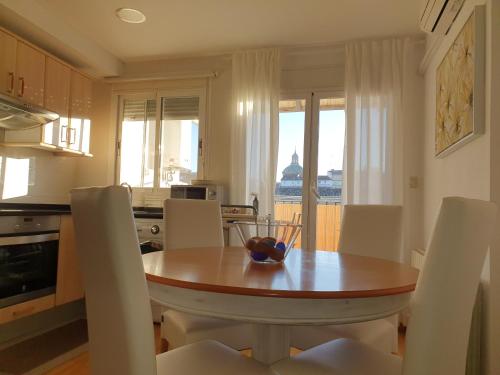 uma cozinha com uma mesa e cadeiras de madeira e uma cozinha com vista em Ático muy luminoso con Parking, em Saragoça
