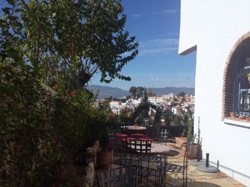 a patio with tables and chairs and a view of a city at Hotel Alkhalifa in Chefchaouene