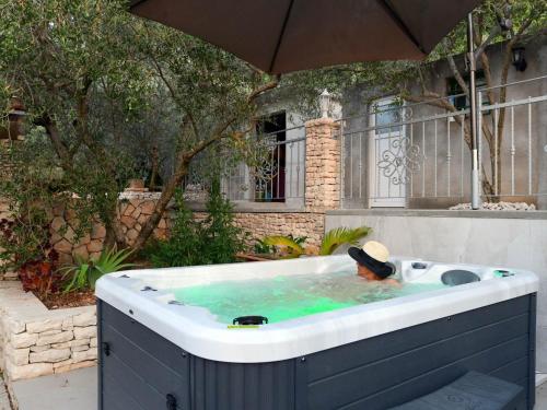 a hot tub in a yard with an umbrella at Stone House Blaca in Blato