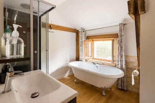 baño con una gran bañera blanca y una ventana en The Barn at Les Chouettes, en Trémolat