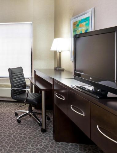 a hotel room with a desk with a television and a chair at Holiday Inn Express & Suites Burlington - Mount Holly by IHG in Westampton Township
