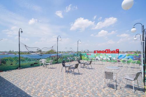 a patio with chairs and tables and a mural at RedDoorz Plus @ Jalan Pemuda Timur Bojonegoro in Bojonegoro