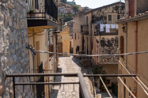 a narrow alley with buildings and a rail at Il Baglio Antico in Prizzi