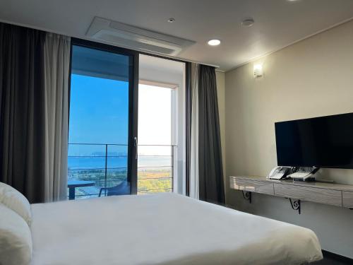 een hotelkamer met een bed en een groot raam bij Incheon Rivieraverium Hotel in Incheon