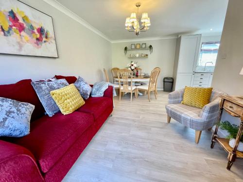 a living room with a red couch and a dining room at Charming 2 Bedroom Bungalow with open plan living in Felixstowe