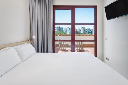 um quarto com uma cama branca e uma janela em B&B HOTEL Madrid Fuenlabrada em Fuenlabrada