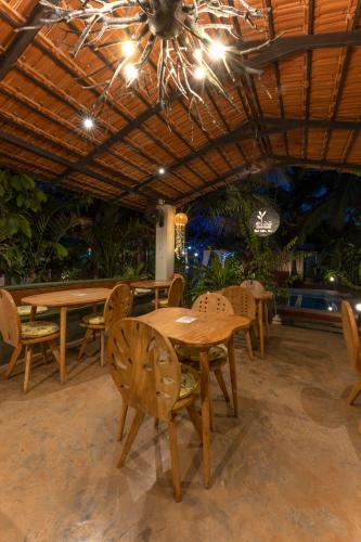 a dining room with tables and chairs and a chandelier at The Hammock Goa in Anjuna