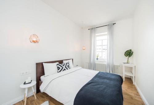 a white bedroom with a bed and a window at Stylish apartment in the heart of Kaunas Old Town in Kaunas
