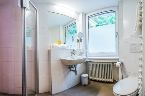 a bathroom with a sink and a toilet at JUFA Hotel Königswinter/Bonn in Königswinter