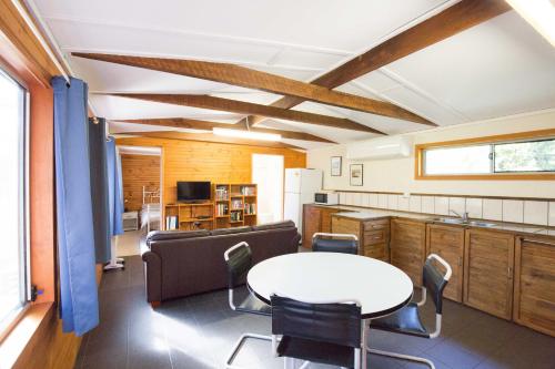 a room with a table and chairs and a kitchen at Wonboyn Cabins in Wonboyn