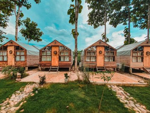 a group of cottages with trees in the background at THE RIVER RUNS CHIANG KLANG in Chiang Klang