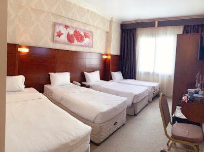 a hotel room with three beds and a desk at Mirage Al Salam Hotel in Al Madinah