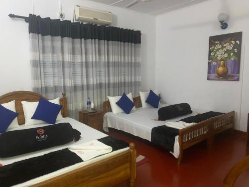 a bedroom with two beds with blue pillows at Sobha Holiday Home in Anuradhapura