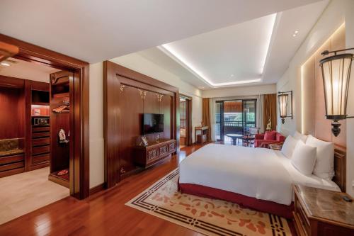a bedroom with a large bed and a living room at InterContinental Xishuangbanna Resort by IHG in Jinghong