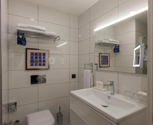 a white bathroom with a sink and a mirror at The Superior Living Batışehir in Istanbul