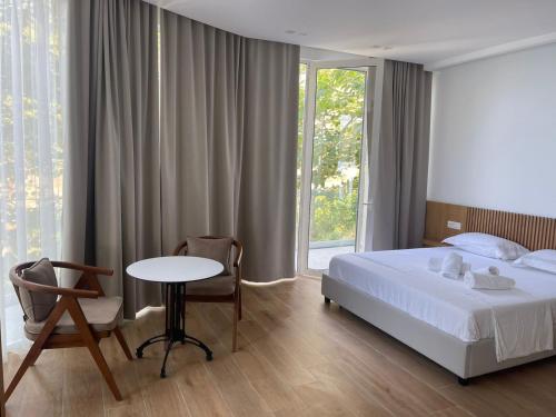 a bedroom with a bed and a table and a window at Hotel Nimfa in Vlorë
