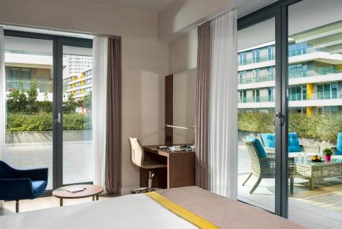 a bedroom with a bed and a desk and a balcony at The Superior Living Batışehir in Istanbul