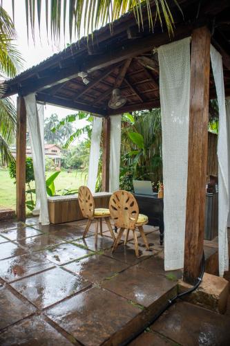 a patio with two chairs and a table and a table at The Hammock Goa in Anjuna